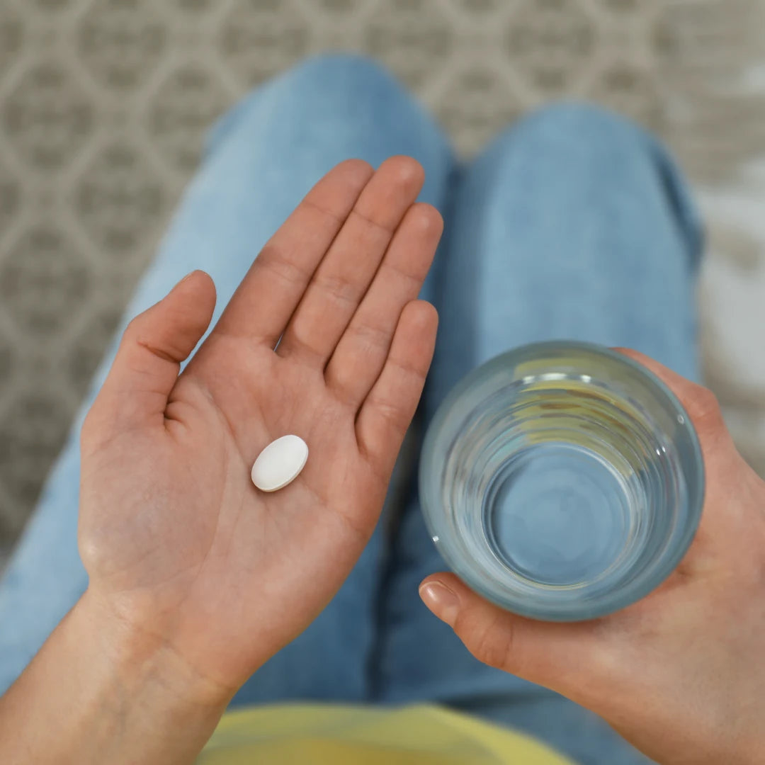 A person holding a tablet and a glass of water